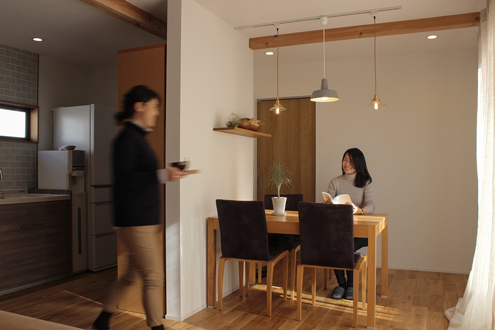 Foto di una piccola sala da pranzo aperta verso il soggiorno scandinava con pareti bianche, pavimento in legno massello medio e pavimento marrone