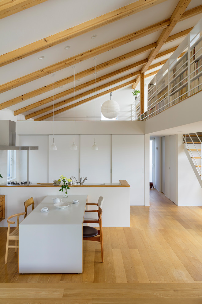 Idee per una sala da pranzo aperta verso la cucina moderna con pareti bianche, pavimento in legno massello medio e pavimento marrone
