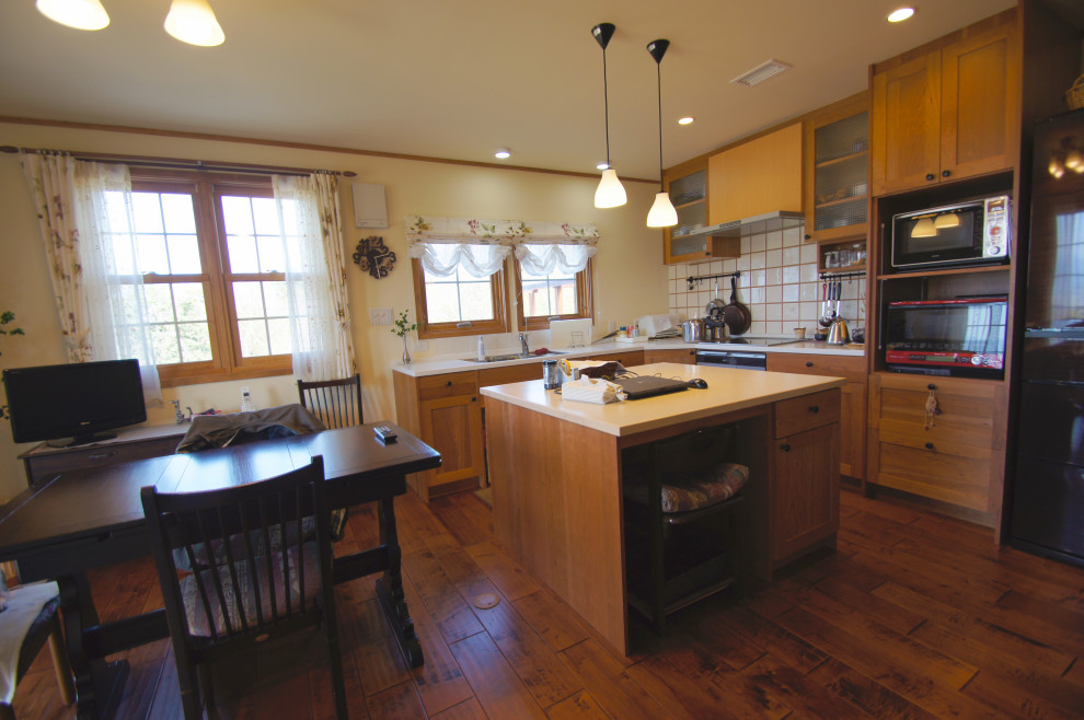 Immagine di una sala da pranzo aperta verso la cucina country con pareti bianche, parquet scuro, stufa a legna, cornice del camino in mattoni e pavimento marrone