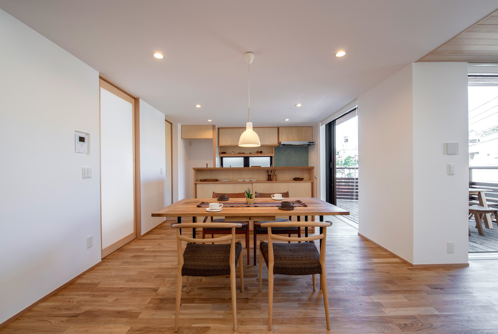 Imagen de comedor de cocina asiático con paredes blancas, suelo de madera en tonos medios y suelo marrón