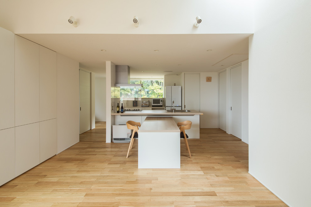 Aménagement d'une salle à manger ouverte sur le salon scandinave avec un mur blanc, un sol en bois brun et un sol beige.