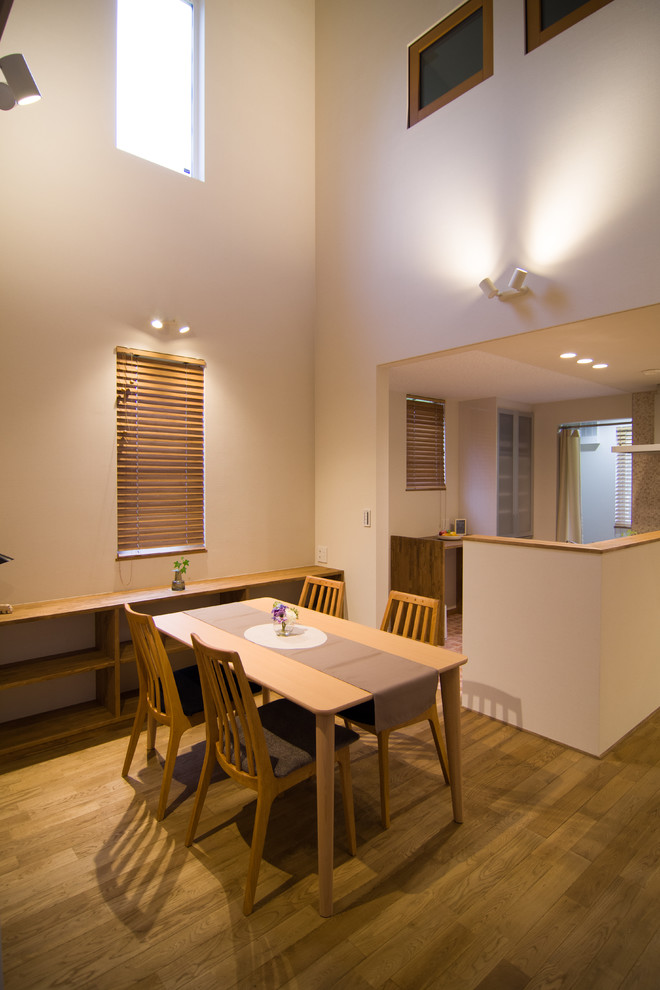 На фото: гостиная-столовая в стиле модернизм с белыми стенами, паркетным полом среднего тона и коричневым полом