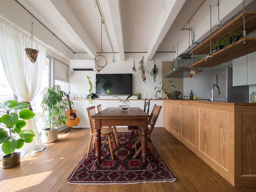 Foto di una sala da pranzo aperta verso la cucina scandinava con pareti bianche e pavimento in legno massello medio