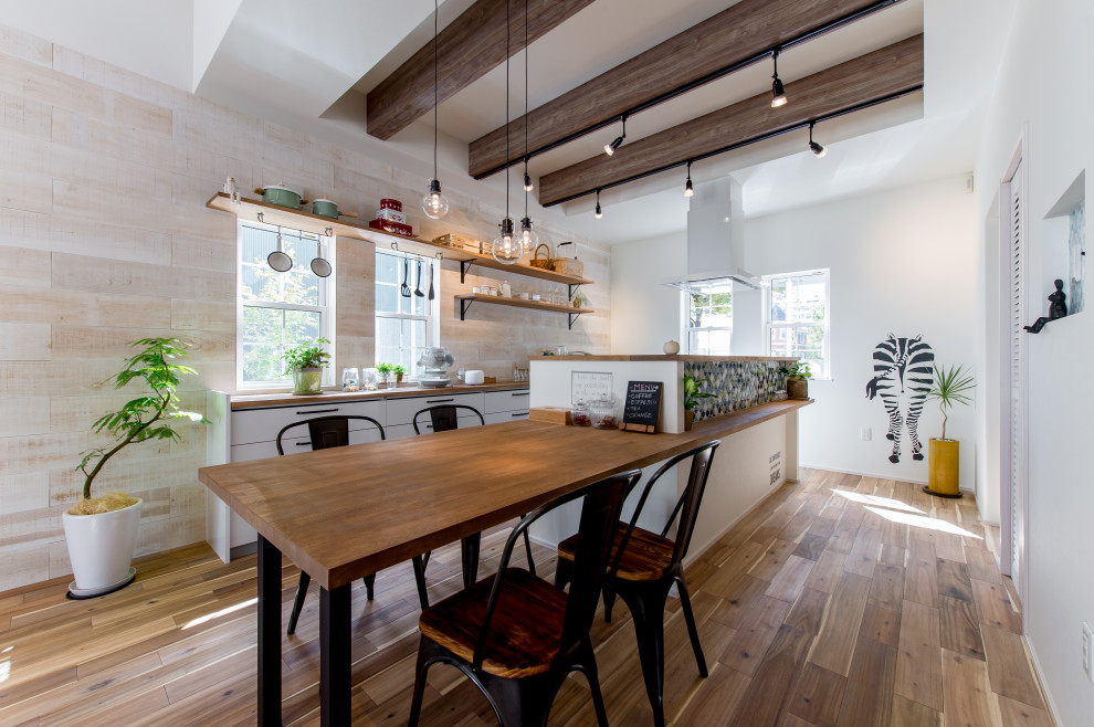 На фото: кухня-столовая с деревянным потолком, белыми стенами и паркетным полом среднего тона с
