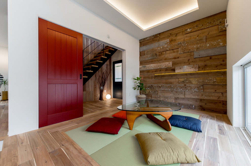 Immagine di una grande sala da pranzo aperta verso il soggiorno etnica con pareti bianche, pavimento in legno massello medio, pavimento marrone e pareti in legno
