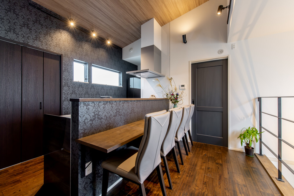 Immagine di una piccola sala da pranzo aperta verso la cucina con pareti nere, parquet scuro, soffitto in carta da parati e carta da parati