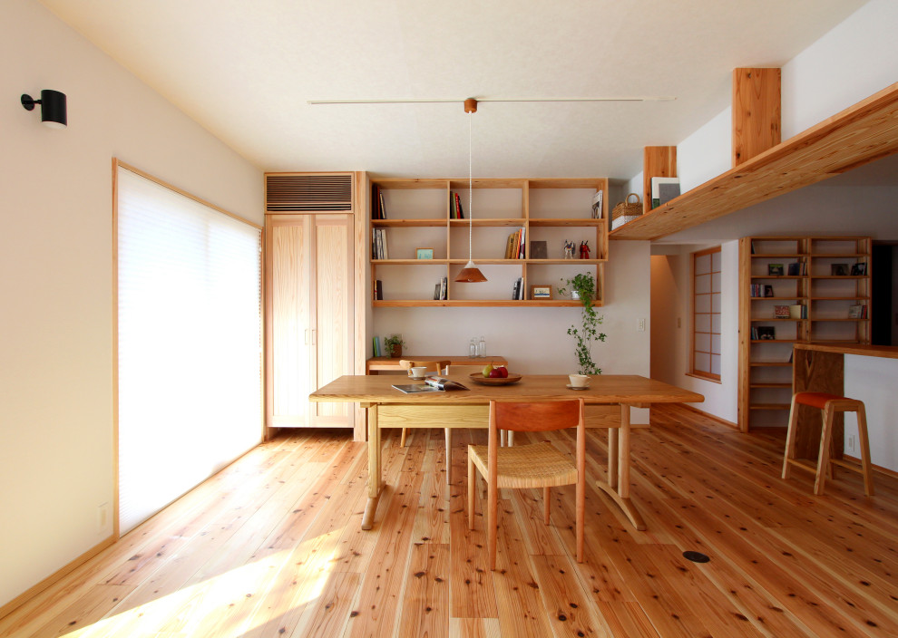 Idee per una sala da pranzo aperta verso la cucina etnica con pareti bianche, pavimento in legno massello medio e pavimento marrone