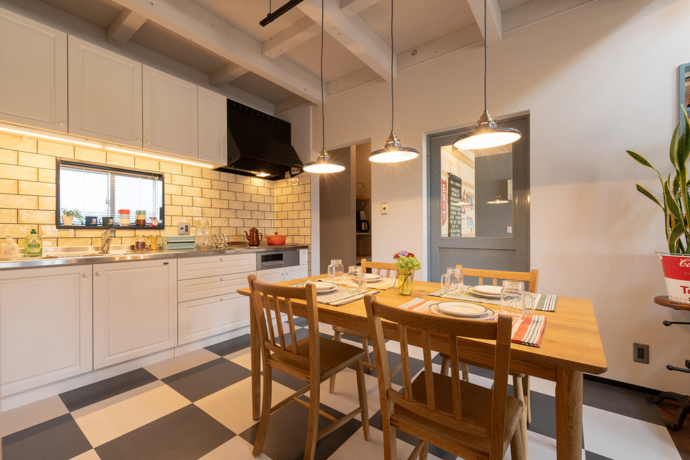 Immagine di una sala da pranzo aperta verso la cucina industriale con pareti bianche e pavimento multicolore