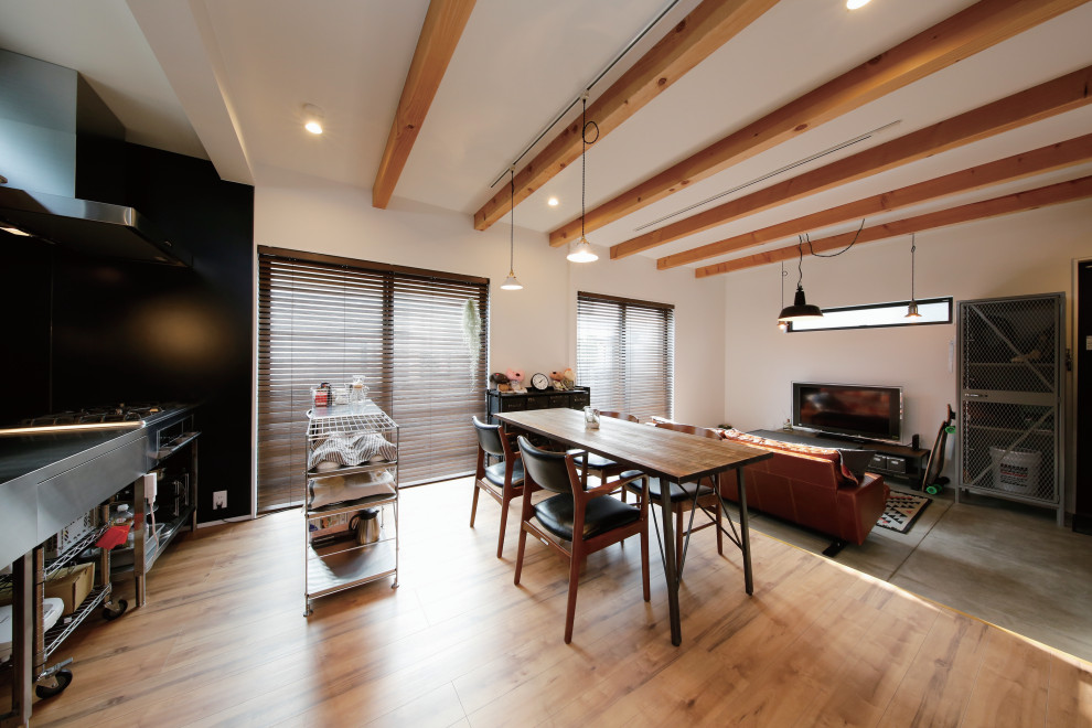 Foto di una sala da pranzo aperta verso il soggiorno industriale di medie dimensioni con pareti bianche, pavimento in legno massello medio e pavimento marrone