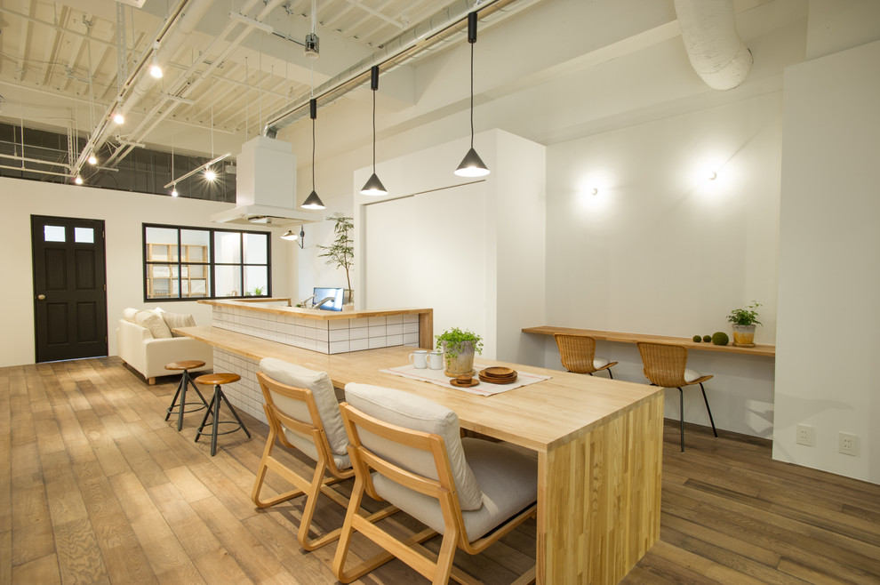 Offenes Industrial Esszimmer mit braunem Holzboden, braunem Boden und weißer Wandfarbe in Tokio