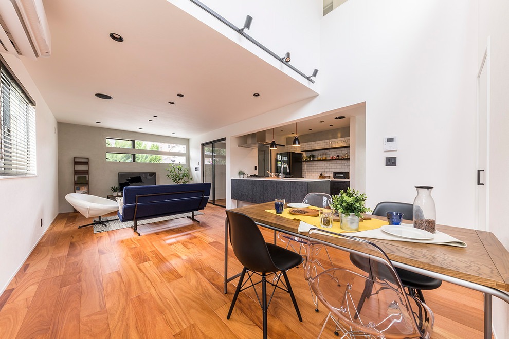 Ispirazione per una sala da pranzo aperta verso il soggiorno contemporanea con pareti bianche, pavimento in legno massello medio e pavimento marrone