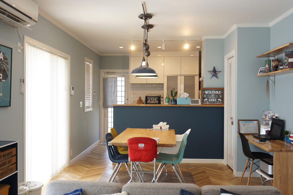 Immagine di una sala da pranzo stile marinaro con pareti blu e parquet chiaro