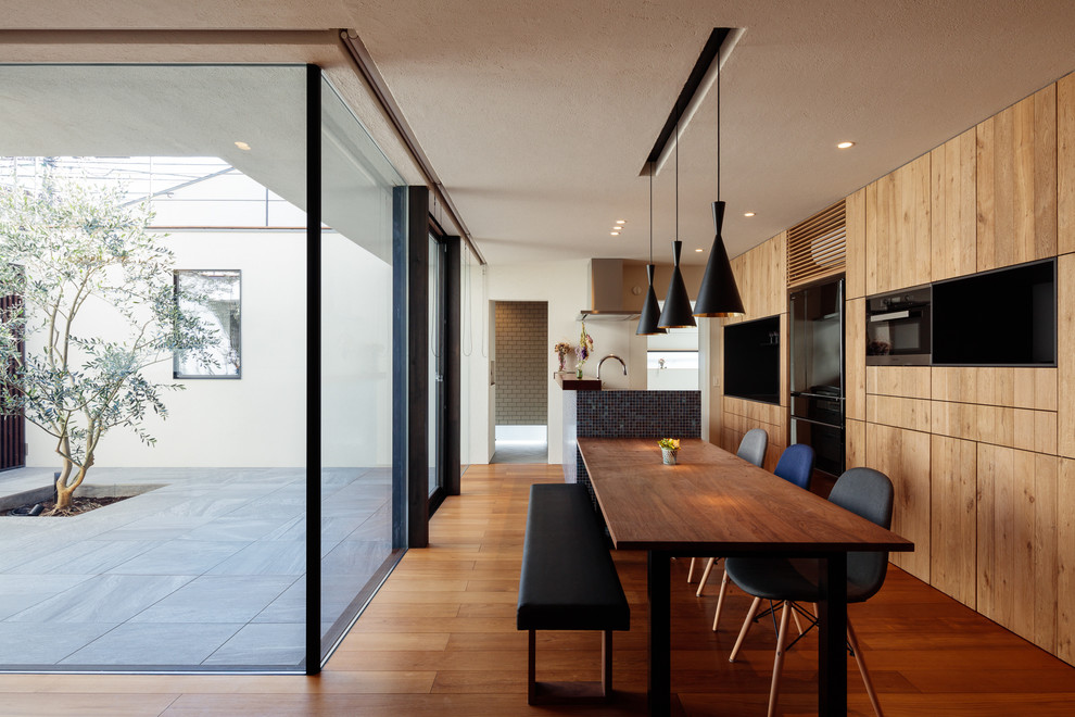 Стильный дизайн: кухня-столовая в восточном стиле с белыми стенами, паркетным полом среднего тона и коричневым полом - последний тренд