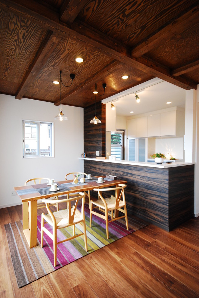 На фото: кухня-столовая в восточном стиле с паркетным полом среднего тона и белыми стенами без камина с