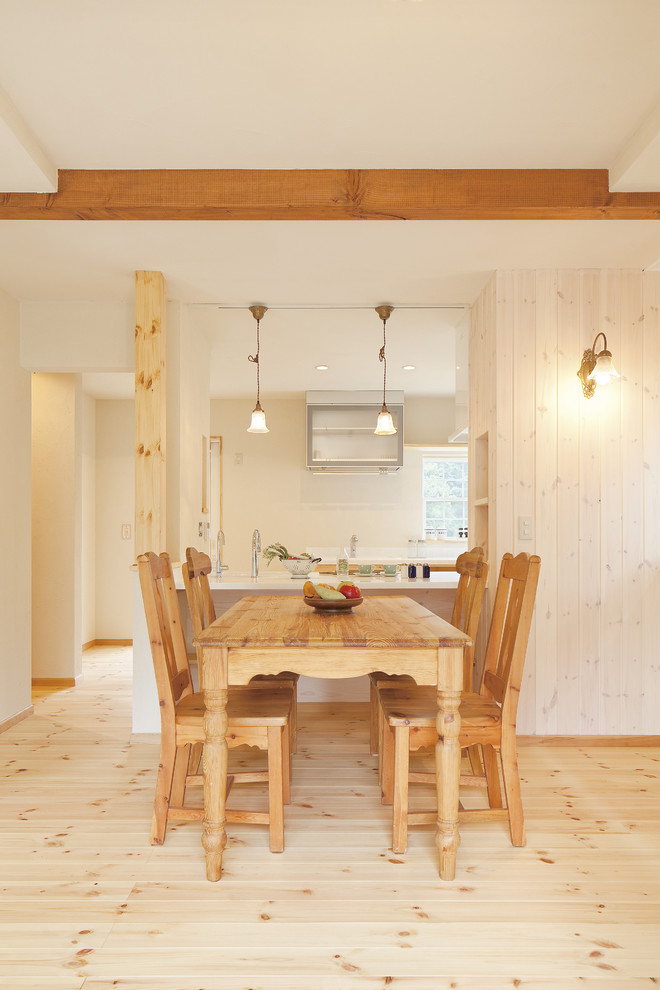 Modelo de comedor de estilo de casa de campo sin chimenea con paredes beige y suelo de madera clara