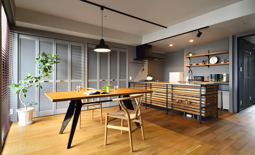 Inspiration pour une salle à manger ouverte sur le salon urbaine avec un mur gris, un sol en bois brun et un sol marron.