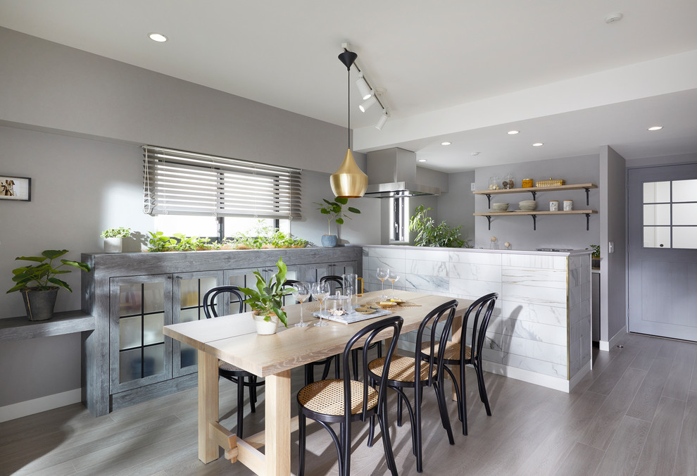 Réalisation d'une salle à manger ouverte sur la cuisine design avec un mur gris, parquet clair et un sol gris.
