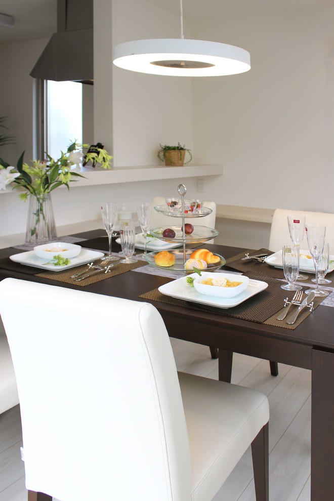 Idee per una sala da pranzo aperta verso il soggiorno minimal con pareti bianche, parquet chiaro e pavimento beige