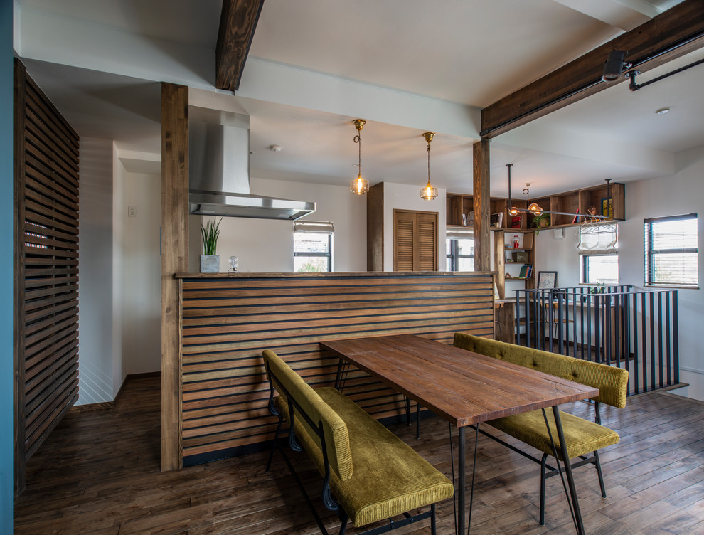 Cette photo montre une salle à manger ouverte sur le salon industrielle de taille moyenne avec un mur blanc, parquet foncé et un sol marron.