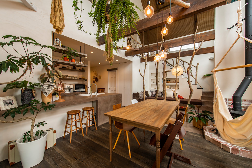 Idée de décoration pour une salle à manger ouverte sur le salon asiatique avec un mur blanc, parquet foncé, un poêle à bois, un manteau de cheminée en brique et un sol marron.