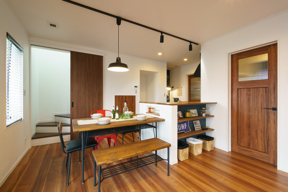 Ispirazione per una sala da pranzo aperta verso il soggiorno stile marinaro con pareti bianche, pavimento in legno massello medio e pavimento marrone