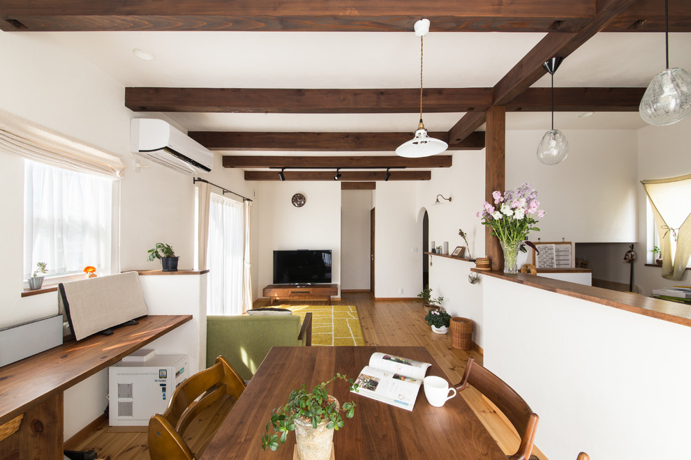 Idée de décoration pour une salle à manger méditerranéenne avec un mur blanc, un sol en bois brun, un sol marron et aucune cheminée.