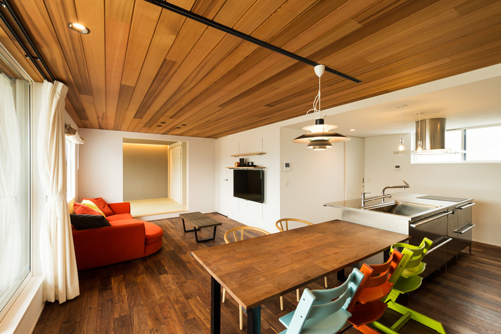 Imagen de comedor minimalista abierto con paredes blancas, suelo de madera oscura y suelo marrón