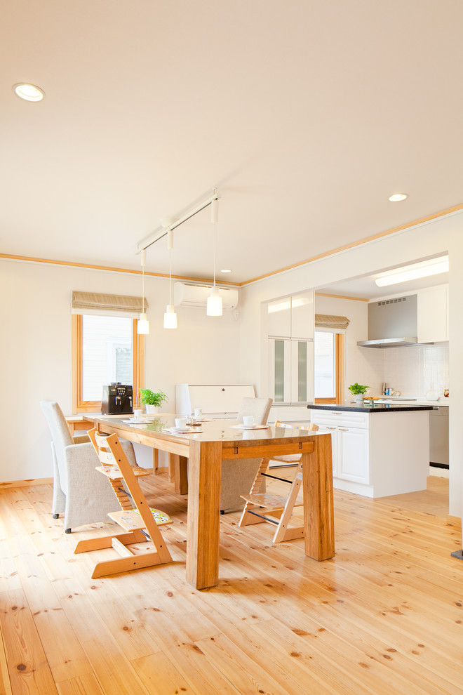 Bild på en stor minimalistisk matplats med öppen planlösning, med vita väggar, ljust trägolv och beiget golv