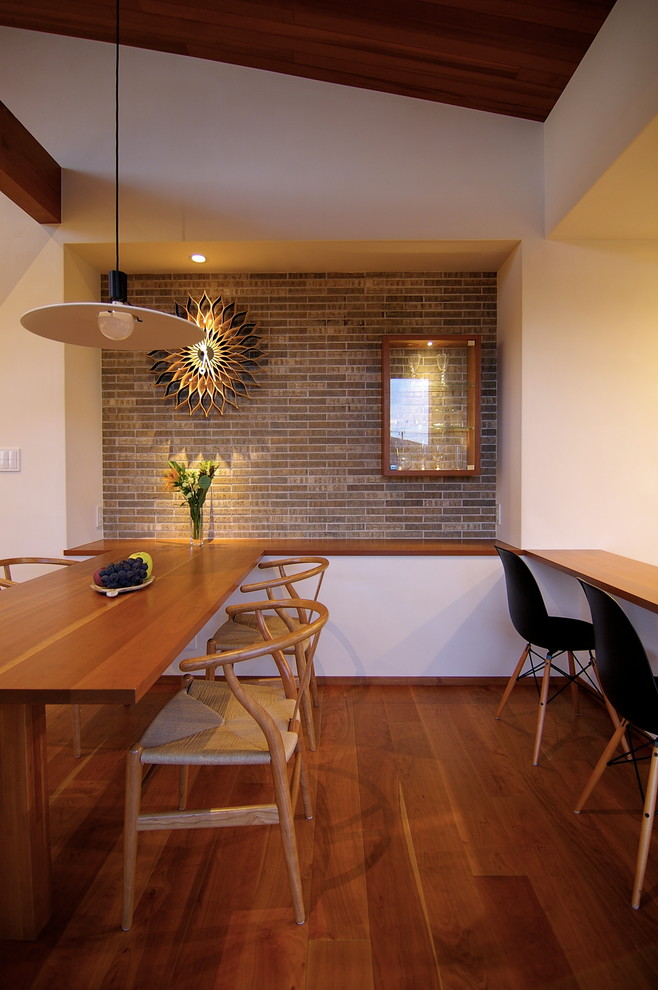 Foto di una sala da pranzo aperta verso il soggiorno moderna con pavimento in legno massello medio, nessun camino, pavimento marrone e pareti bianche
