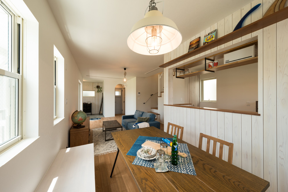 Пример оригинального дизайна: гостиная-столовая в морском стиле с белыми стенами, паркетным полом среднего тона и коричневым полом
