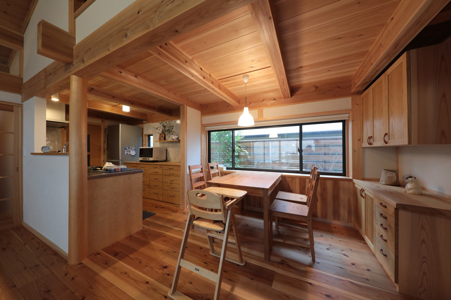 Aménagement d'une salle à manger ouverte sur la cuisine asiatique de taille moyenne avec un mur blanc et un sol en bois brun.