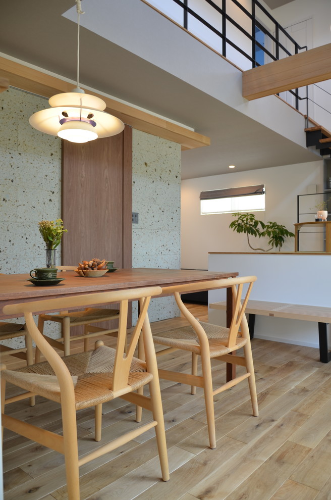 Cette image montre une salle à manger ouverte sur le salon minimaliste de taille moyenne avec un mur gris, parquet clair et un sol marron.