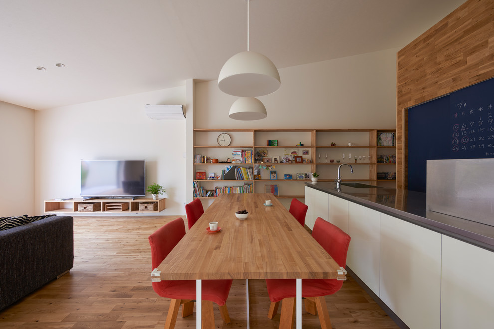 Aménagement d'une salle à manger ouverte sur le salon scandinave avec un mur blanc et un sol en bois brun.