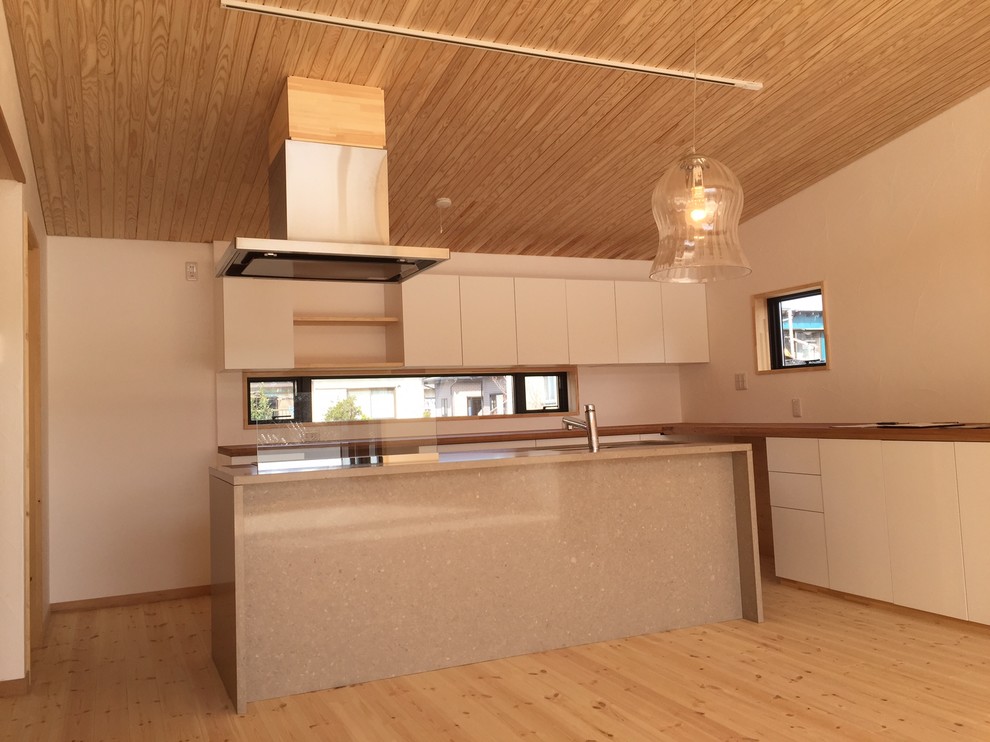 Exempel på en mellanstor minimalistisk matplats med öppen planlösning, med vita väggar, ljust trägolv och beiget golv