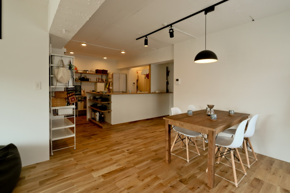 Immagine di una piccola sala da pranzo aperta verso il soggiorno minimal con pareti bianche, pavimento in legno massello medio, pavimento beige e pareti in perlinato