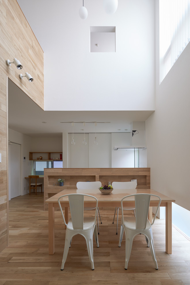 Imagen de comedor de cocina minimalista con paredes blancas y suelo de madera clara