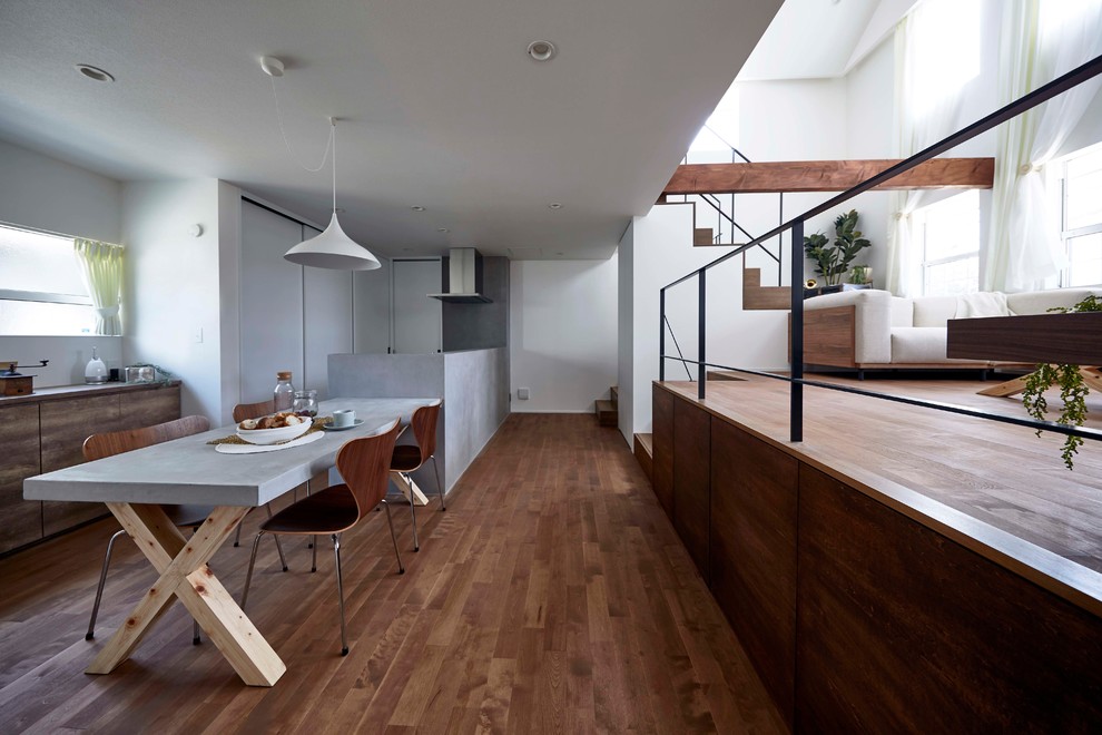 Immagine di una sala da pranzo aperta verso il soggiorno contemporanea con pareti bianche, pavimento in legno massello medio e pavimento marrone