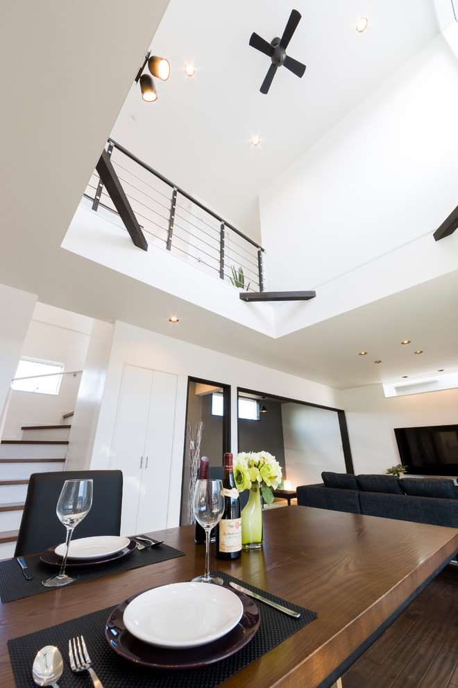 Esempio di una sala da pranzo aperta verso il soggiorno minimalista con pareti bianche, parquet scuro e pavimento marrone