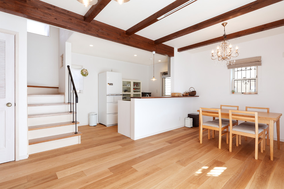 Esempio di una sala da pranzo aperta verso il soggiorno etnica con pareti bianche, parquet chiaro e pavimento marrone