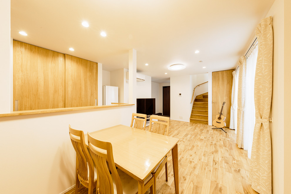 Photo of a medium sized modern open plan dining room in Tokyo Suburbs with white walls, light hardwood flooring, brown floors, a wallpapered ceiling and wallpapered walls.