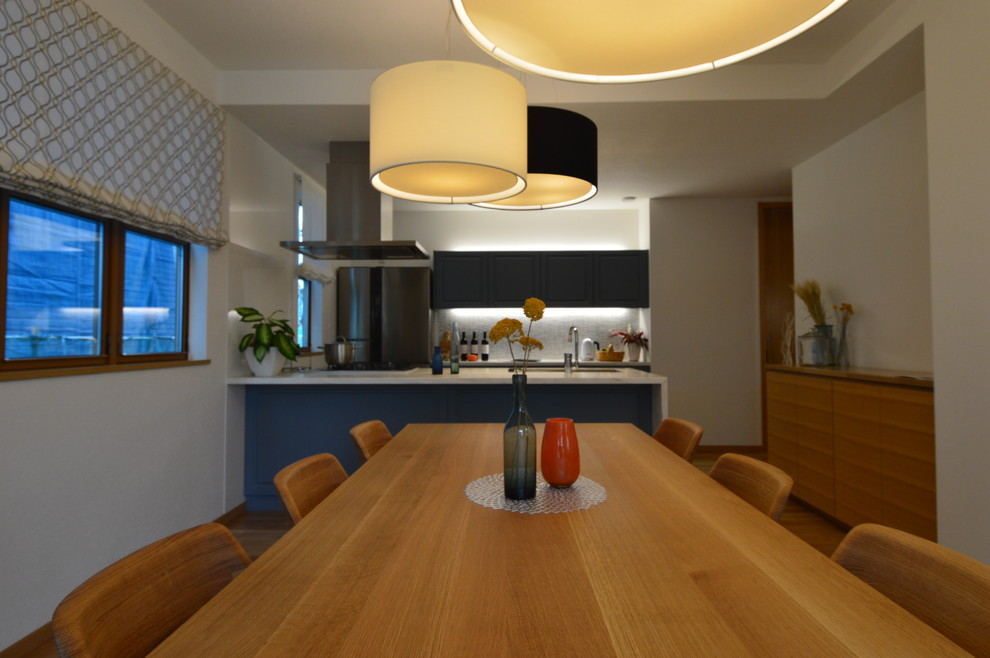 Aménagement d'une grande salle à manger ouverte sur la cuisine moderne avec un mur orange, un sol en bois brun et aucune cheminée.