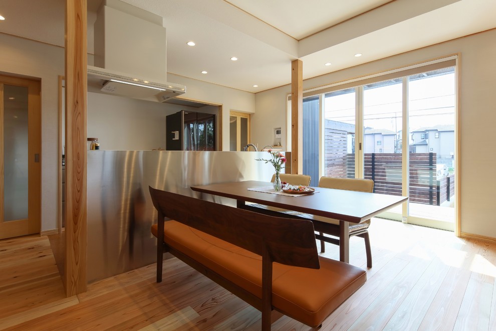 Inspiration pour une salle à manger ouverte sur le salon design avec un mur blanc, parquet clair et un sol marron.