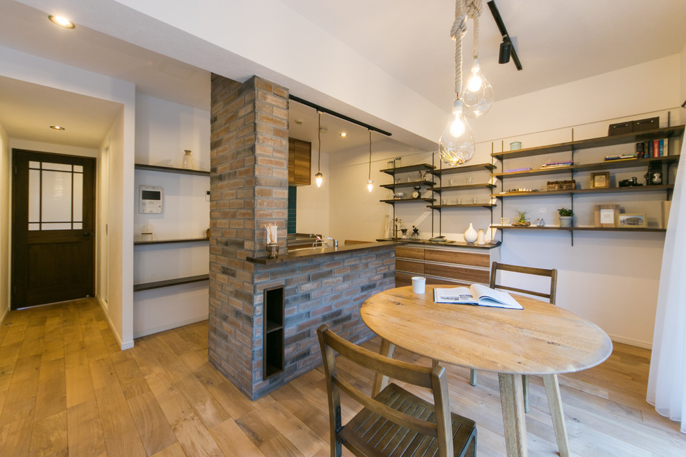 Cette photo montre une salle à manger ouverte sur le salon rétro avec un mur blanc, parquet clair et un sol marron.