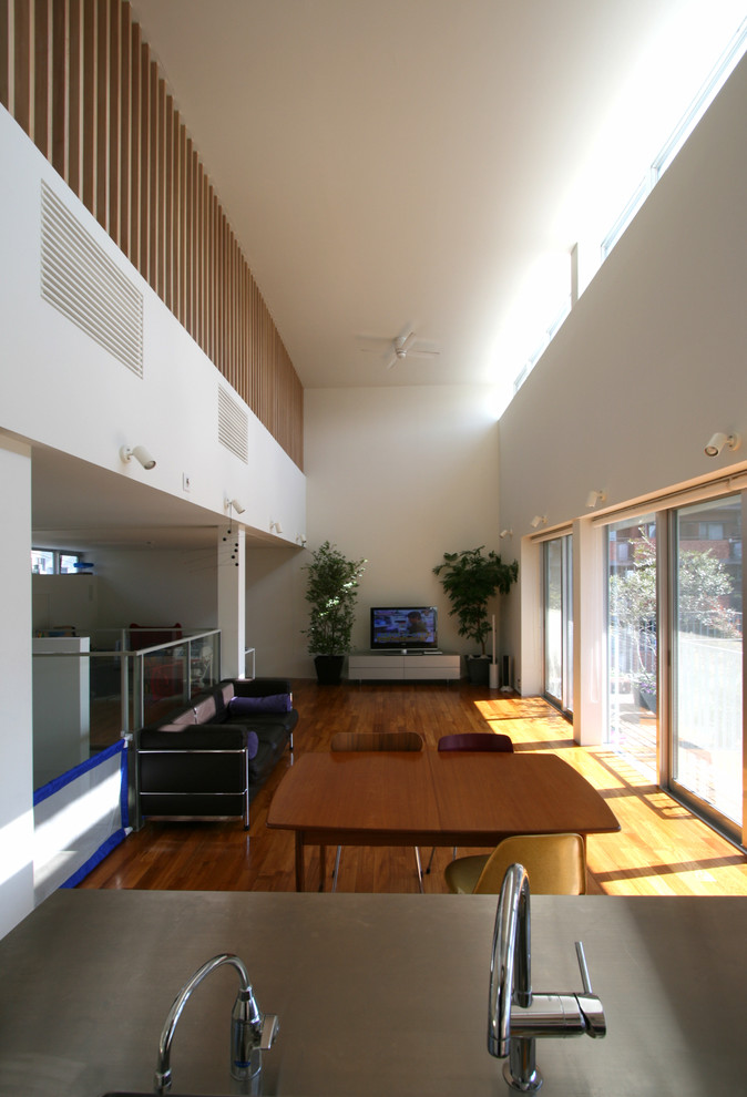Cette photo montre une salle à manger ouverte sur le salon moderne avec un mur blanc, un sol en bois brun et un sol marron.