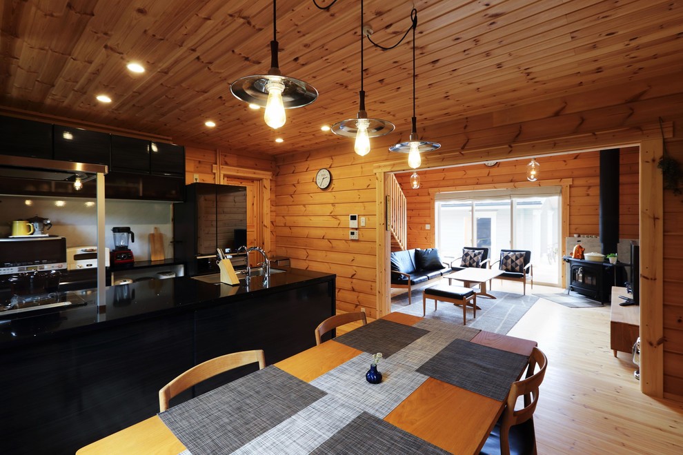 Réalisation d'une salle à manger ouverte sur le salon asiatique avec un mur marron, un sol en bois brun, une cheminée d'angle, un manteau de cheminée en béton et un sol marron.