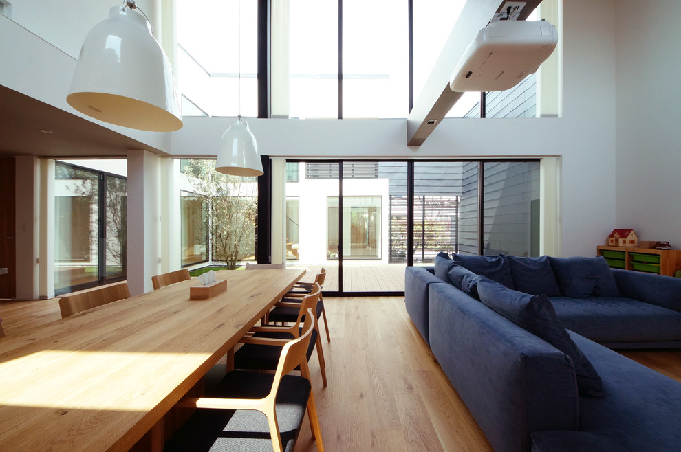 Offenes Modernes Esszimmer mit weißer Wandfarbe, braunem Holzboden und braunem Boden in Tokio