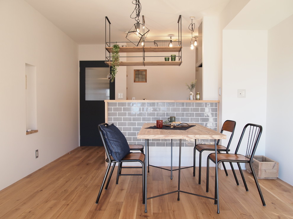 Immagine di una sala da pranzo aperta verso il soggiorno industriale con pareti bianche, parquet chiaro e pavimento marrone