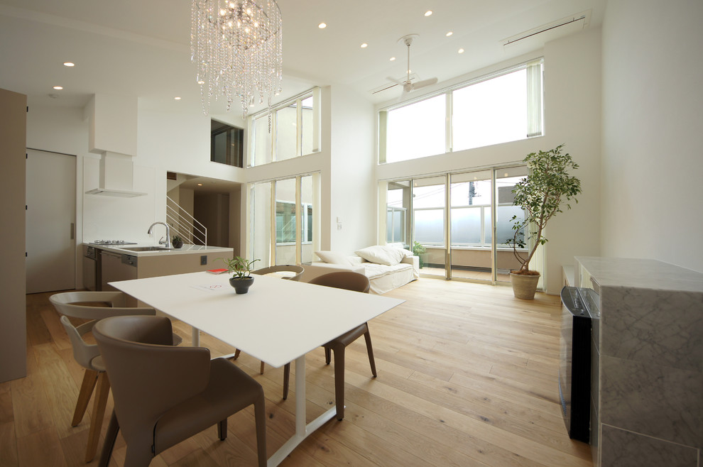 Foto di una grande sala da pranzo aperta verso il soggiorno minimalista con pareti bianche, parquet chiaro e pavimento beige