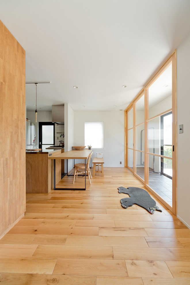 Idee per una sala da pranzo aperta verso il soggiorno design di medie dimensioni con pareti bianche, pavimento in legno massello medio e nessun camino