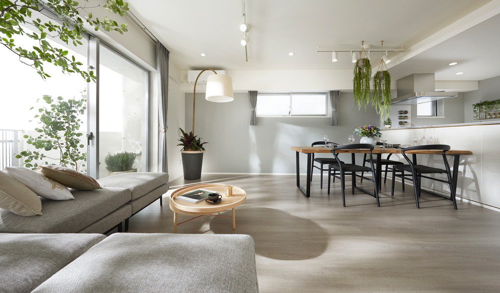 Idee per una sala da pranzo aperta verso il soggiorno design con pareti grigie, pavimento in legno verniciato e pavimento grigio